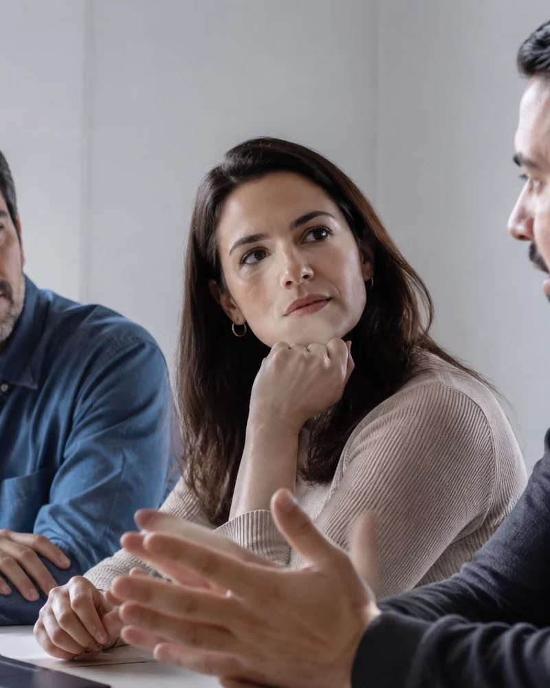 Microfone deitado sobre a mesa, com a roda de participantes fora de foco ao fundo